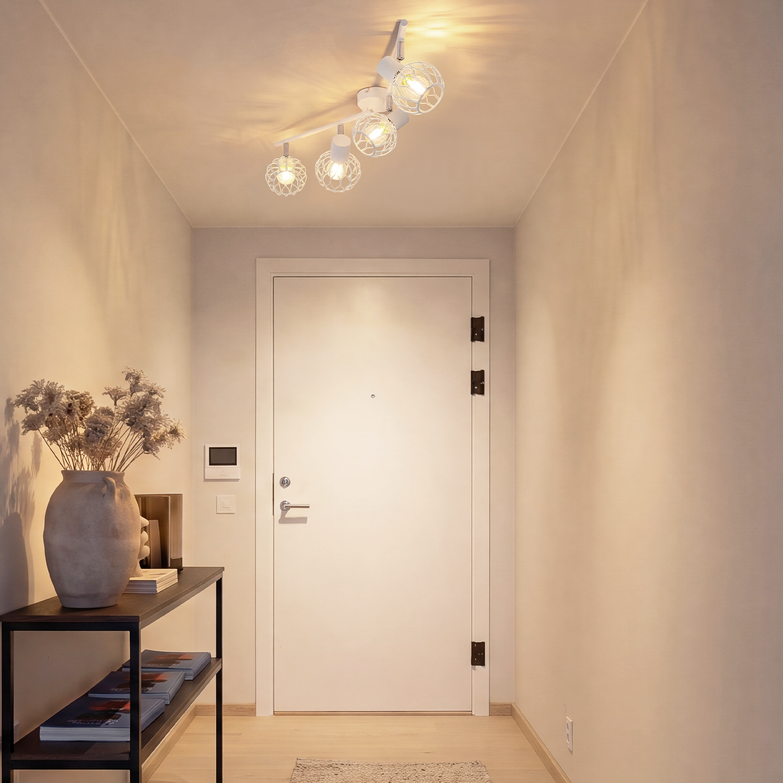 Un pasillo luminoso con una puerta blanca, una lámpara de techo y una mesa consola con jarrón.