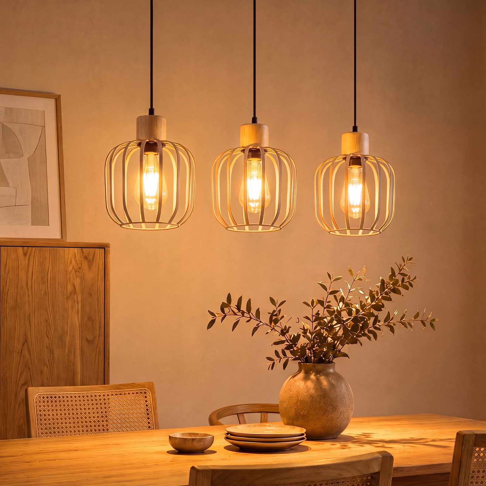 Drei Holzkäfig-Hängelampen leuchten über einem gedeckten Holztisch mit Vase und Zweigen.