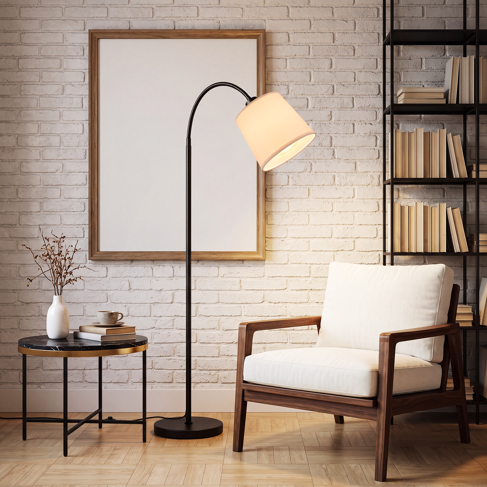 Sillón blanco, lámpara de pie negra, mesa pequeña con libros y un marco de fotos grande ante una pared de ladrillos.
