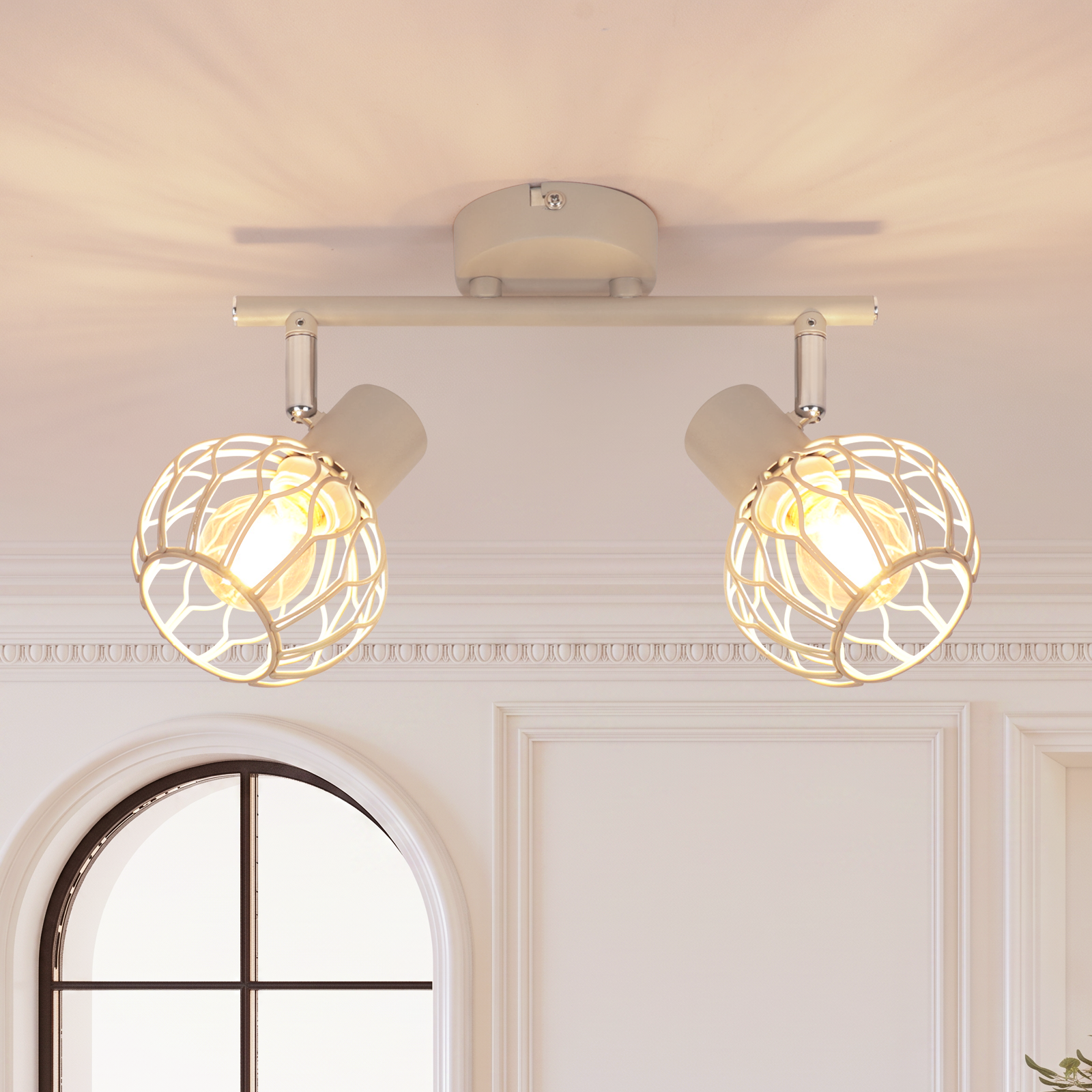 Eine weiße Deckenlampe mit zwei runden Drahtgitter-Schirmen leuchtet an einer weißen Wand.