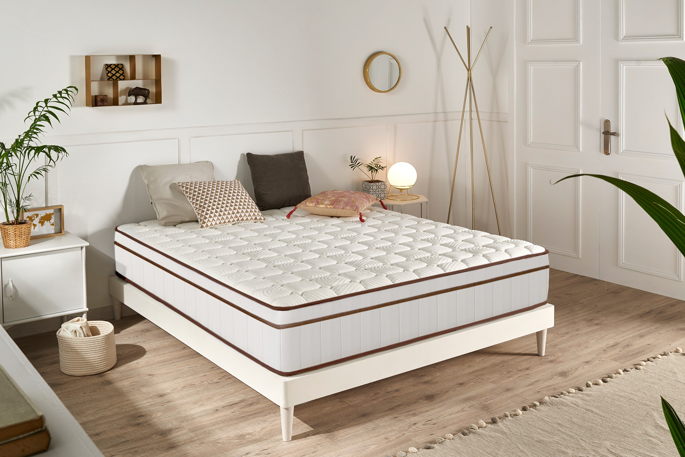 Una cama blanca con colchón acolchado se encuentra en un dormitorio luminoso con suelo de madera.