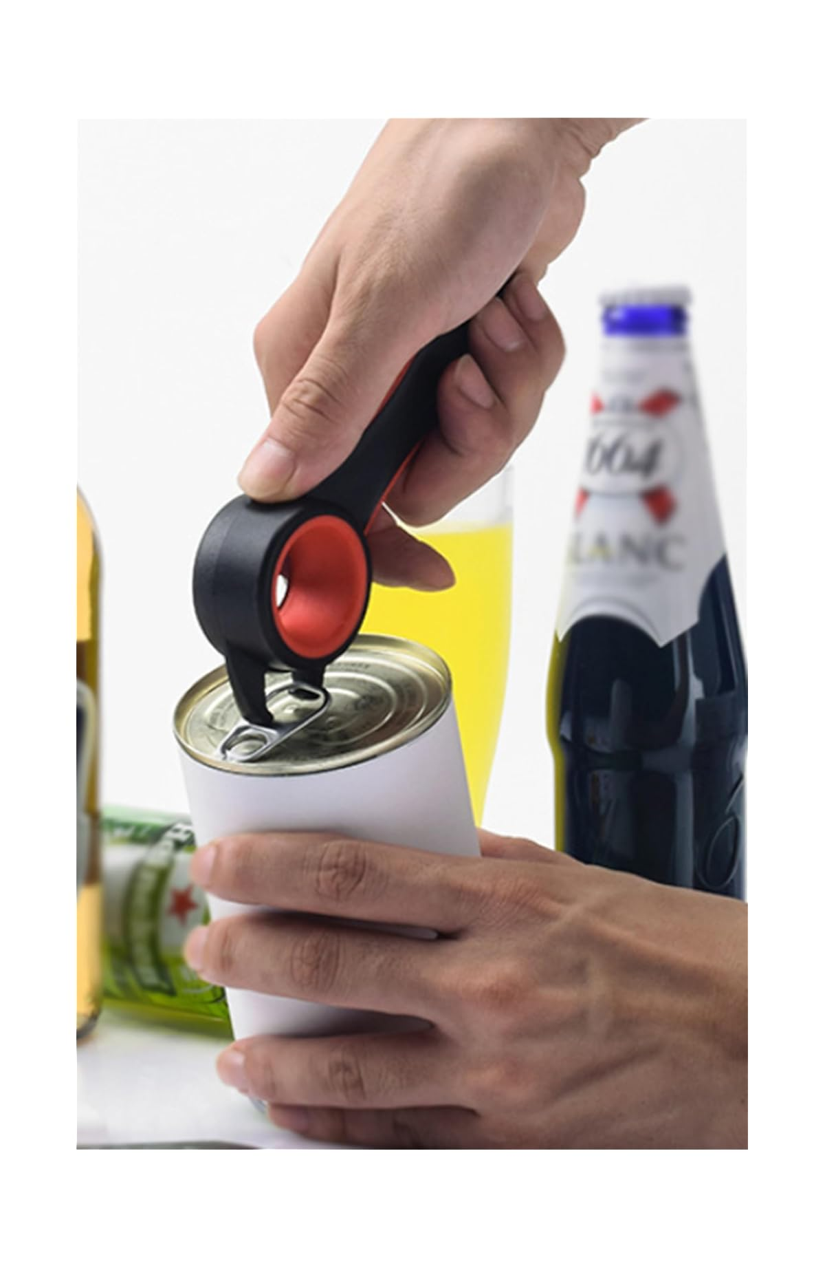 Eine Hand öffnet eine Weißblechdose mit einem schwarz-roten Dosenöffner, im Hintergrund sind Flaschen und ein Glas zu sehen.