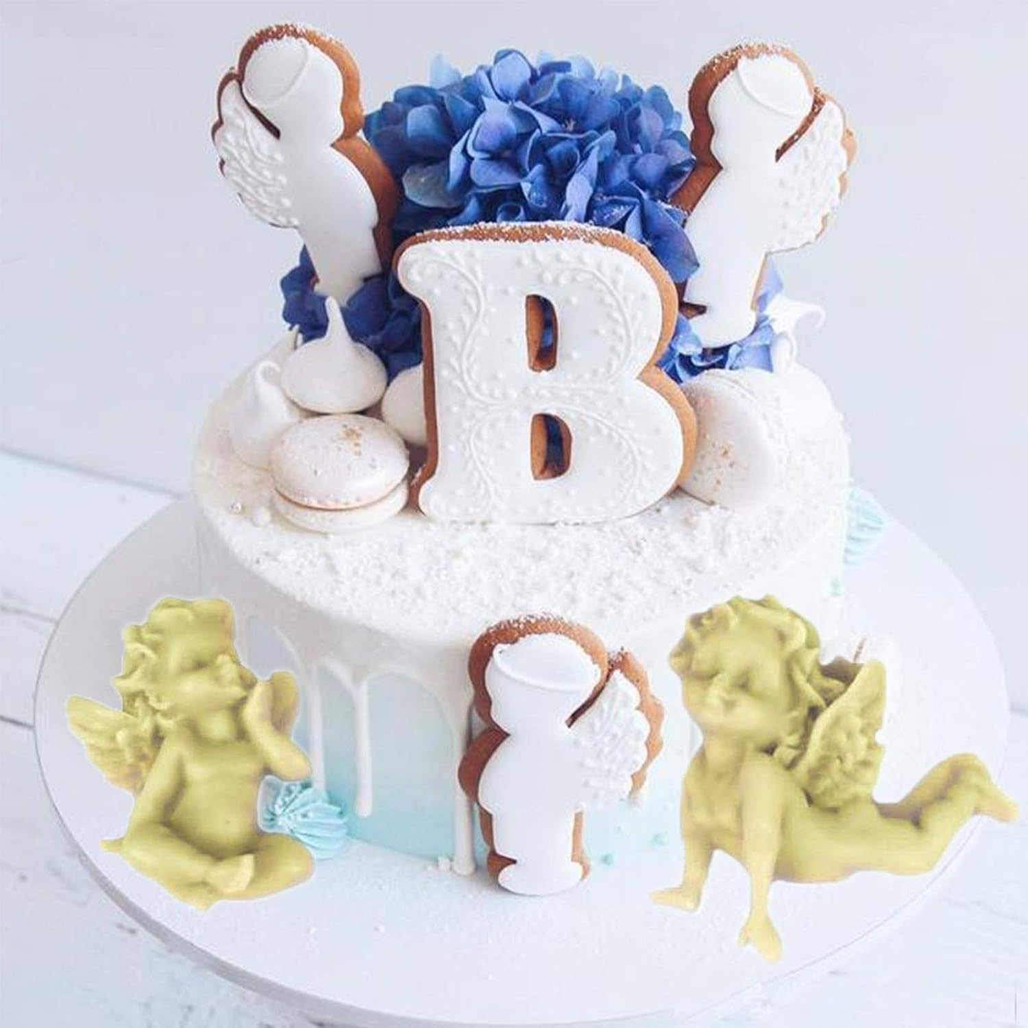 Eine weiß glasierte Torte mit blauen Blumen, Engelsplätzchen, dem Großbuchstaben B und kleinen Putten.