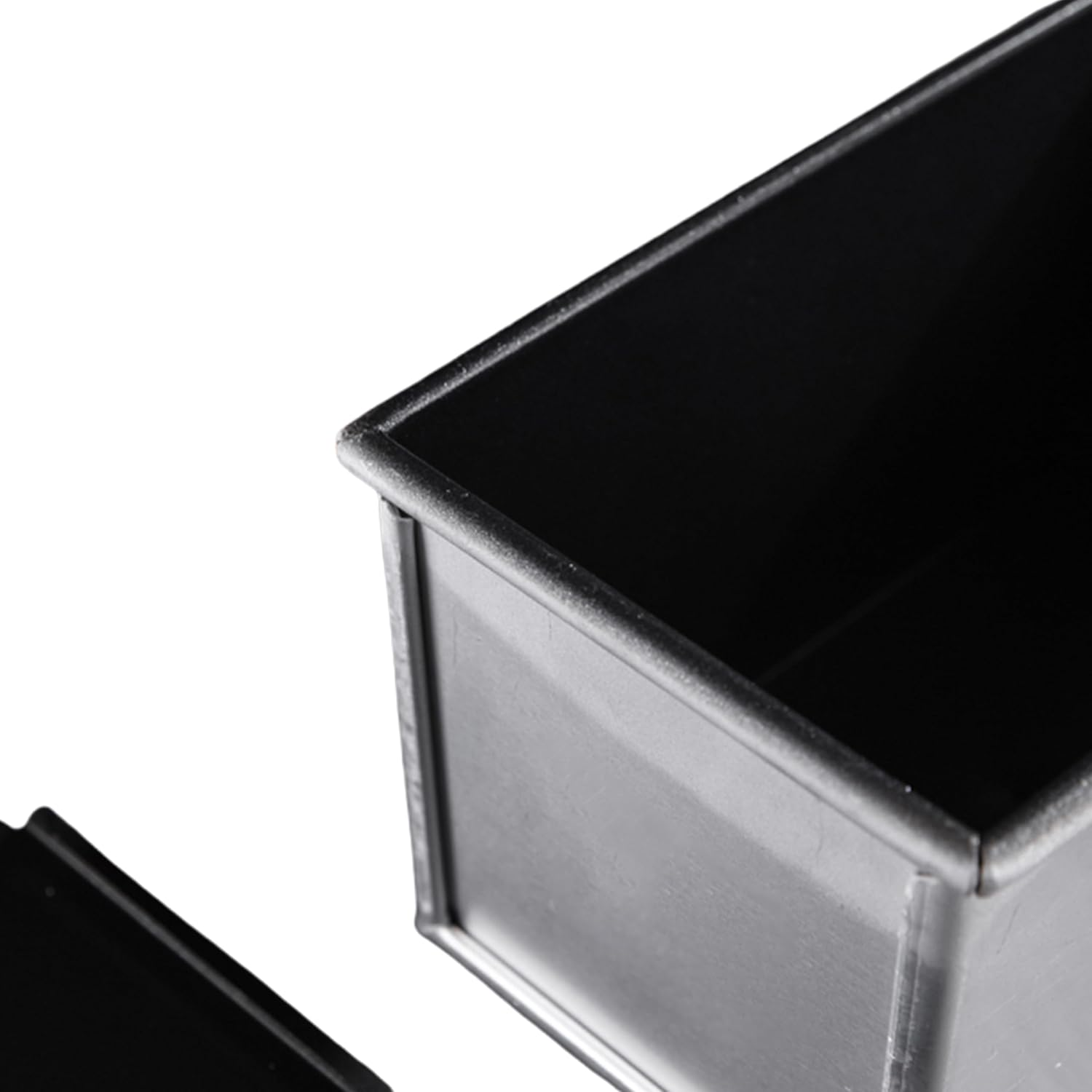 Eine schwarze Kastenbackform mit separatem Deckel auf weißem Hintergrund.