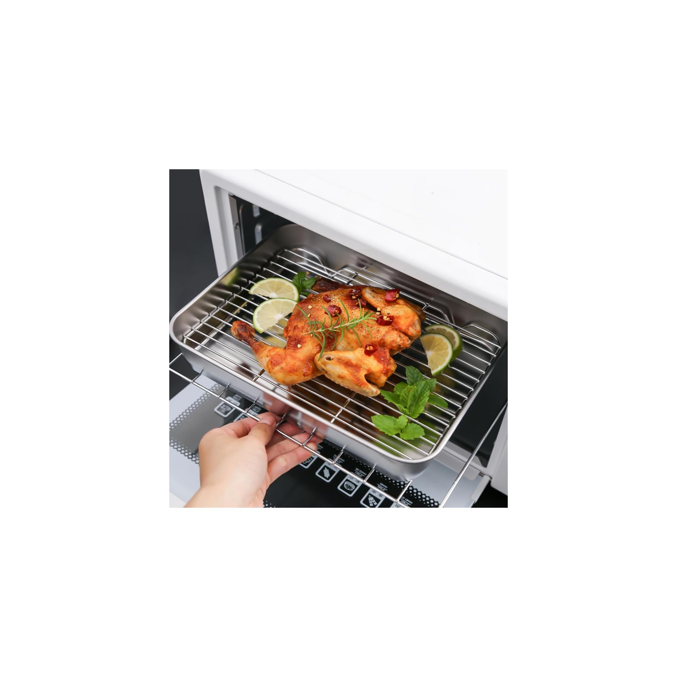 Eine Hand zieht einen Ofenrost mit gebratenem Hähnchen, Limetten und Kräutern aus einem Ofen.