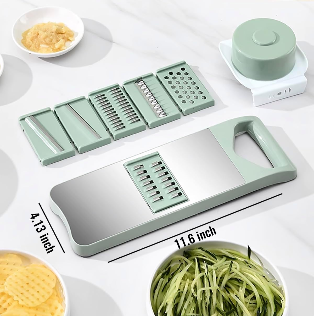 Ein grüner Gemüseschneider mit Klingen, Handschutz und Schüsseln mit Gemüse auf einem weißen Tisch.