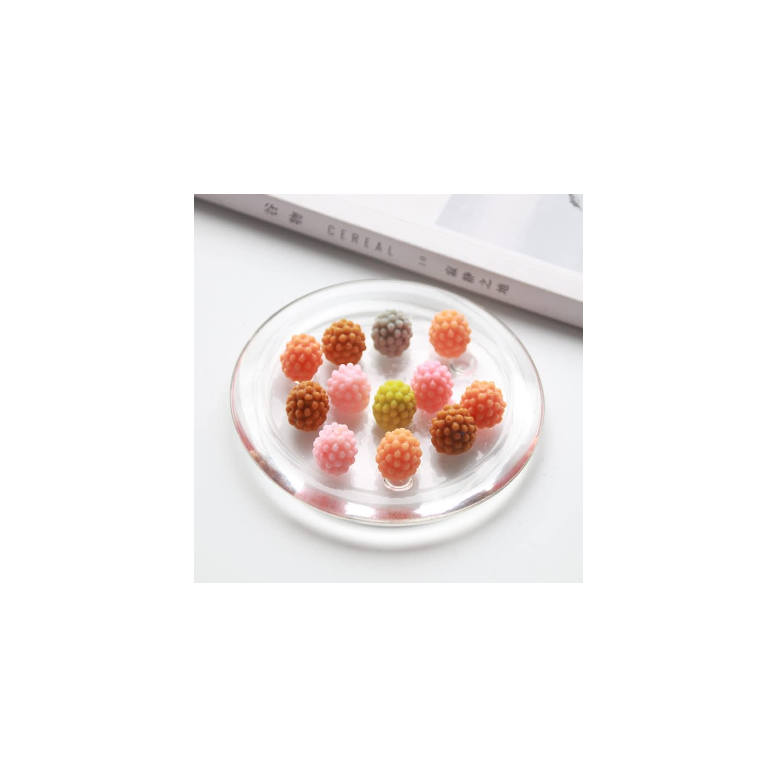Bunte, perlenartige Süßigkeiten in verschiedenen Farben auf einem Glas Teller vor einem Cereal-Magazin.