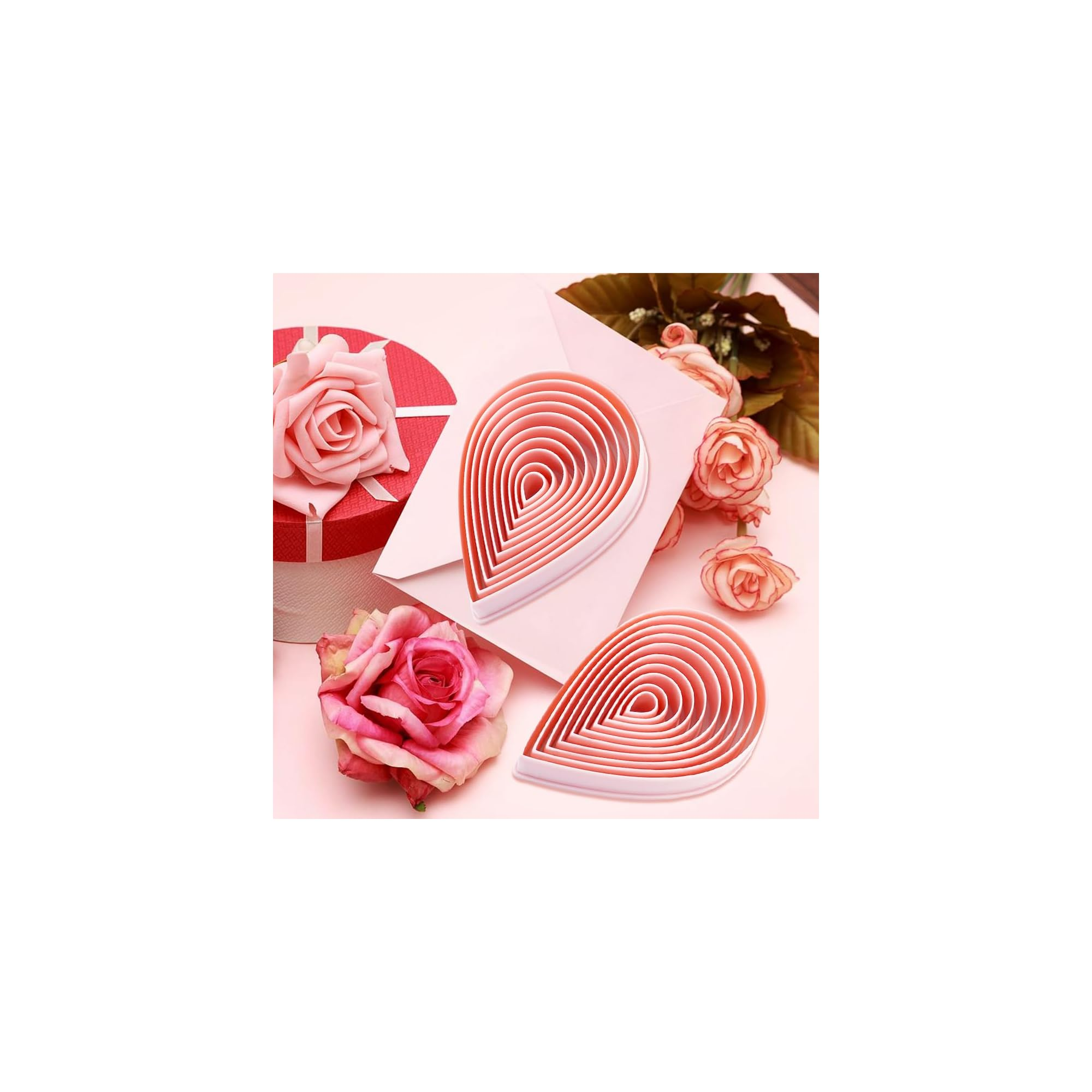 Rosa blütenförmige Ausstechformen, umgeben von Rosen und einer Geschenkbox vor rosa Hintergrund.