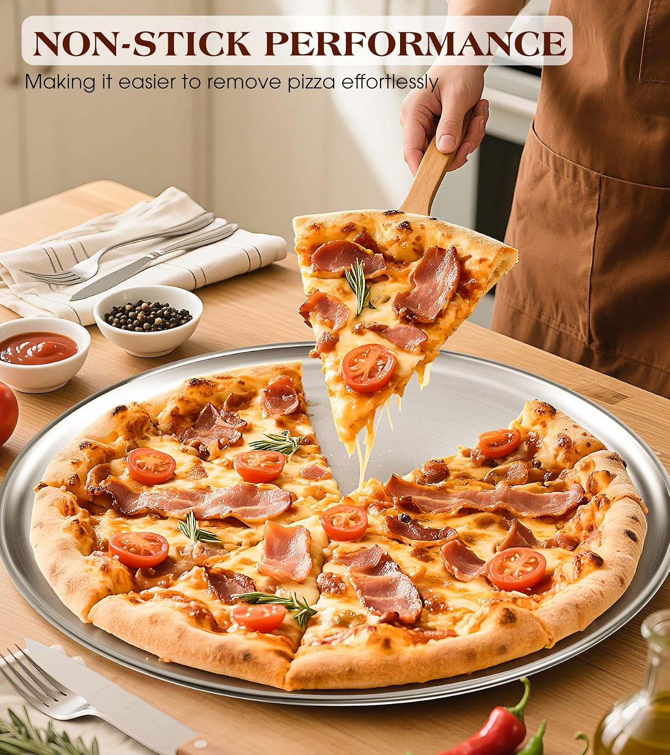 Eine Hand hebt ein Stück Pizza mit Speck und Tomaten von einer metallenen Pizzapatte auf Holztisch.
