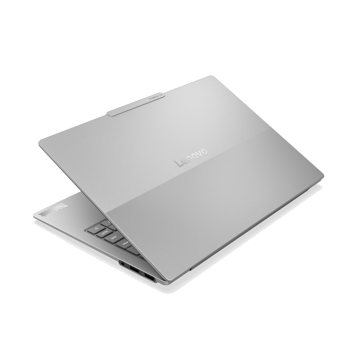 Un ordenador portátil Lenovo plateado está parcialmente abierto sobre un fondo negro.