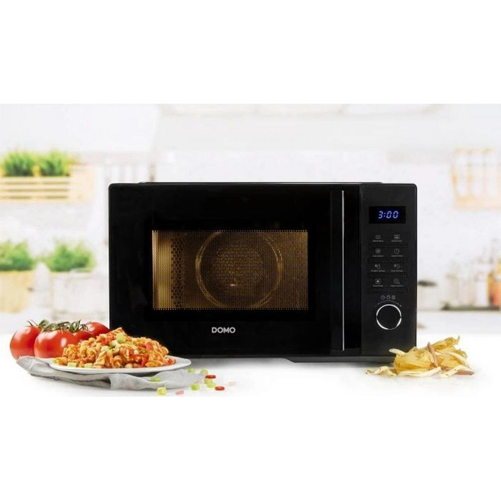 Micro-ondes noir Domo sur un comptoir avec un plat de pâtes et des tomates.