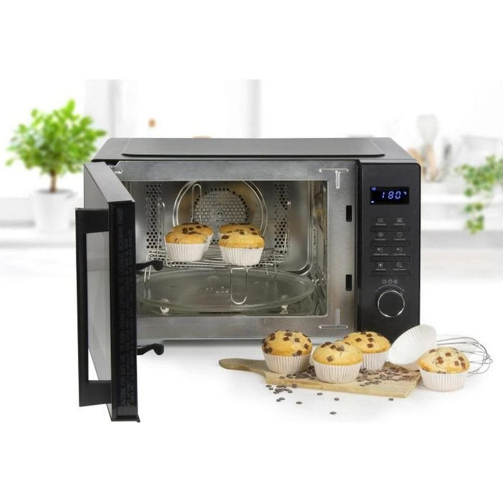 Un four ouvert avec des muffins sur une grille à l'intérieur et d'autres muffins sur une planche devant dans une cuisine.