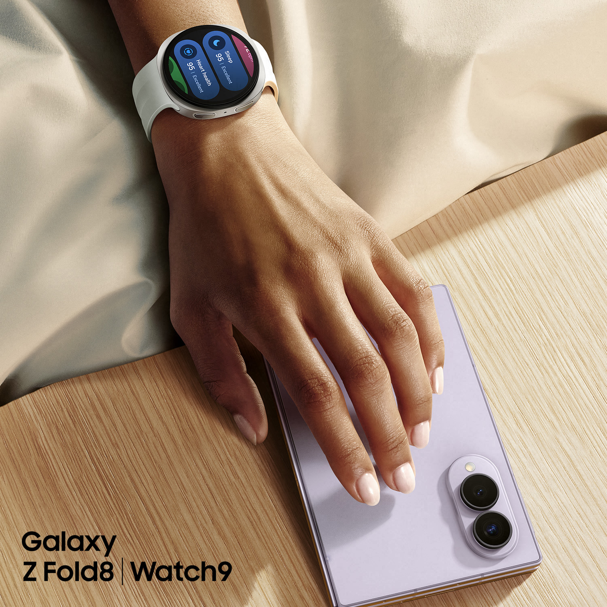 Una mano con smartwatch poggia su uno smartphone viola chiaro su una superficie di legno.