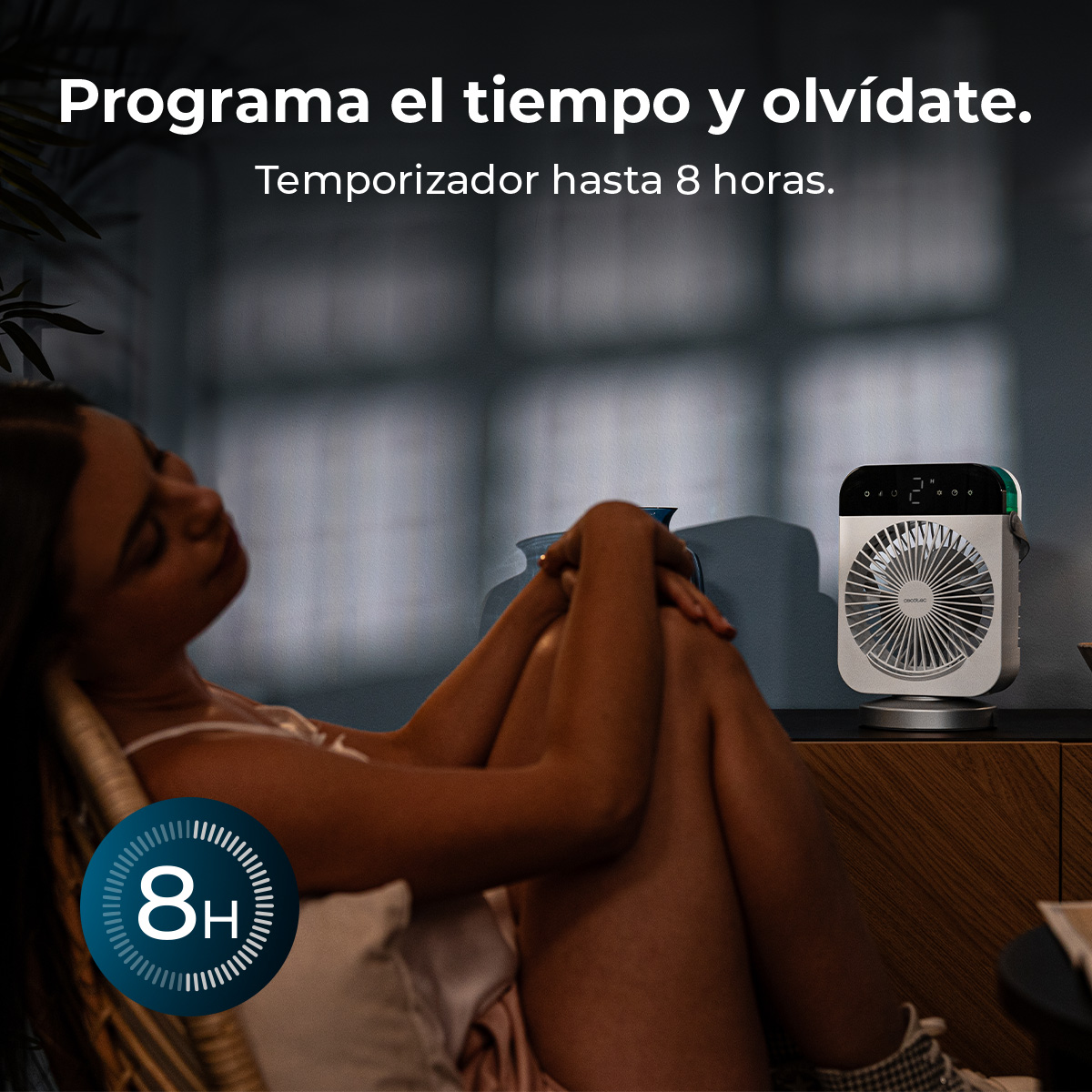 Una mujer se relaja en una silla mientras un pequeño ventilador de mesa está cerca.