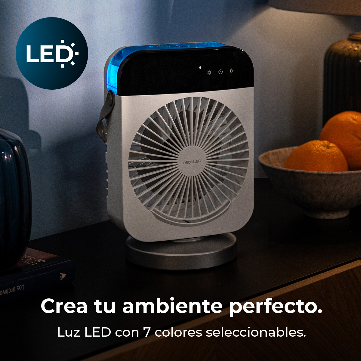 Ventilador portátil blanco Cecotec con luz LED azul en una mesa junto a naranjas.