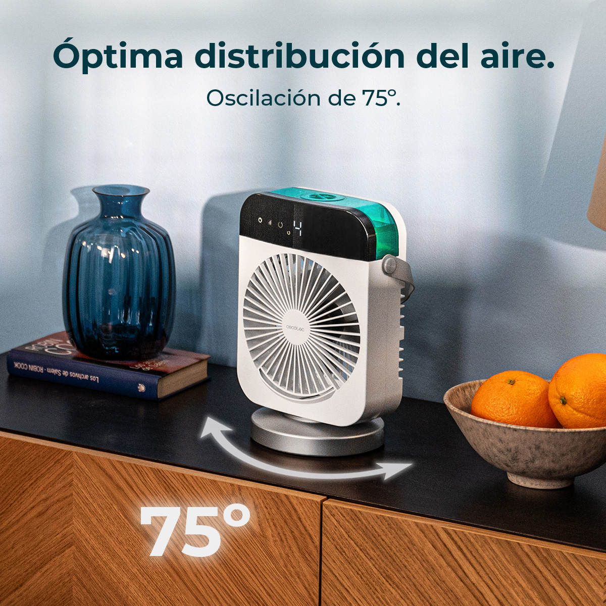Un mini ventilador blanco en una mesa de madera con un jarrón azul y naranjas.