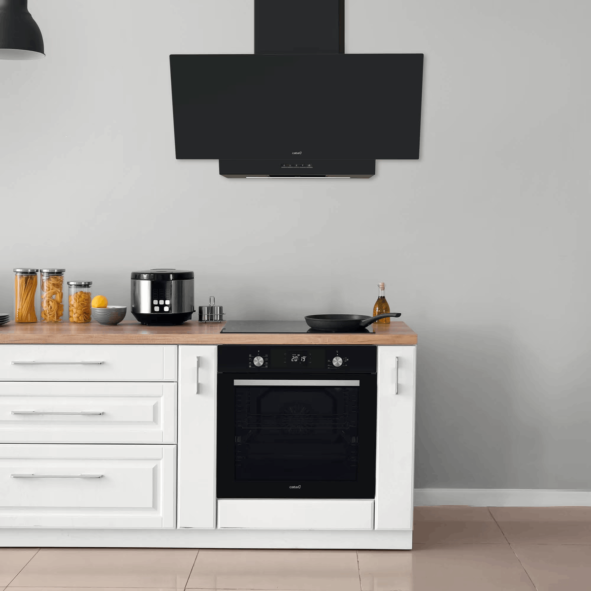 Cocina moderna con muebles blancos, horno negro, campana extractora, encimera de madera y tarros.