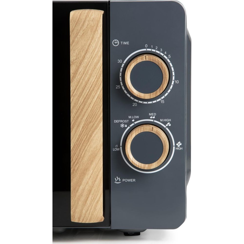 Gros plan d'un micro-ondes gris avec deux boutons effet bois et une poignée en bois verticale sur la porte.