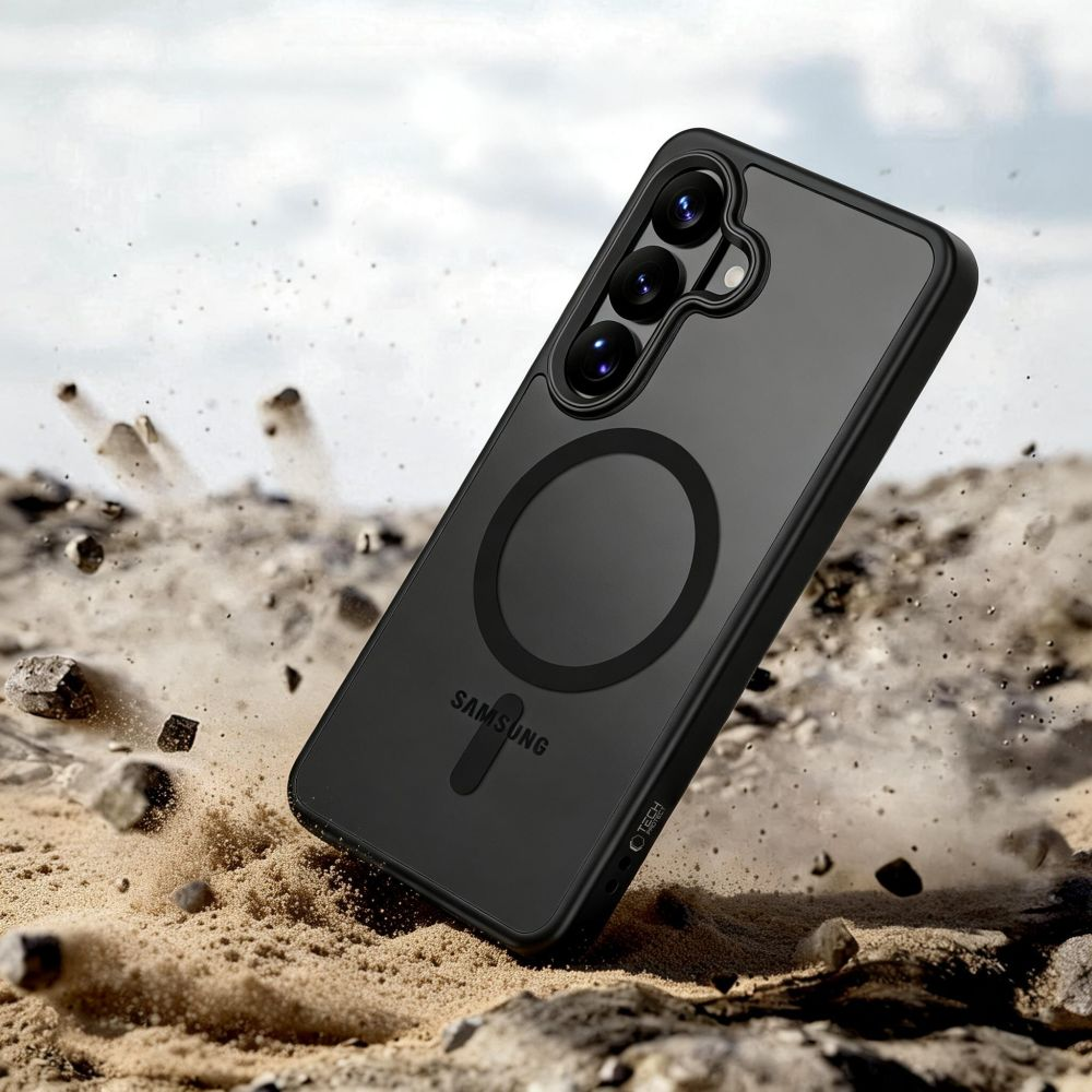 Ein schwarzes Samsung-Smartphone in einer Schutzhülle steht auf sandigem Boden, während Staubwolken aufgewirbelt werden.