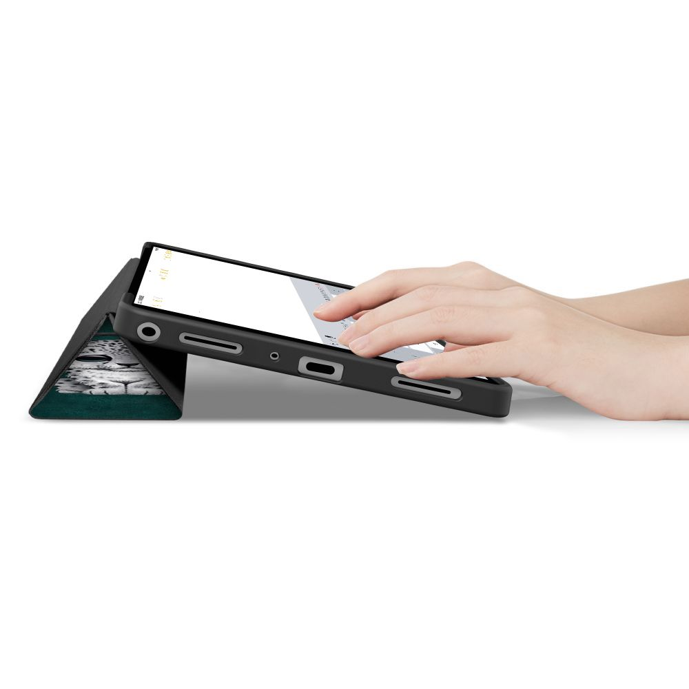 Mani che scrivono su un tablet in custodia nera con supporto con motivo animale su sfondo bianco.