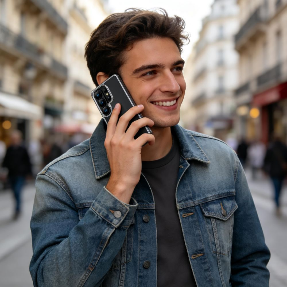 Ein junger Mann mit Jeansjacke telefoniert lächelnd in einer belebten Straße.