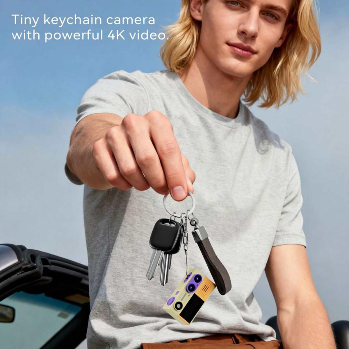 Ein blondhaariger Mann hält einen Schlüsselring mit einer winzigen Kamera und dem Text 'Tiny keychain camera'.
