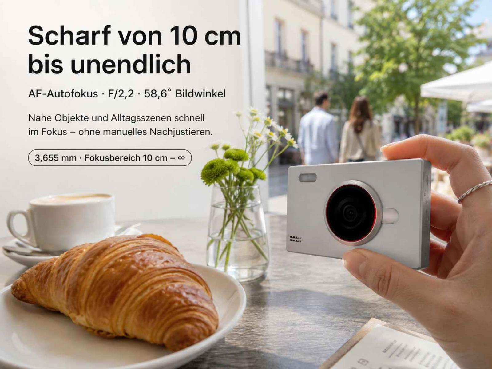 Hand hält weiße Kamera am Tisch mit Croissant und Text.