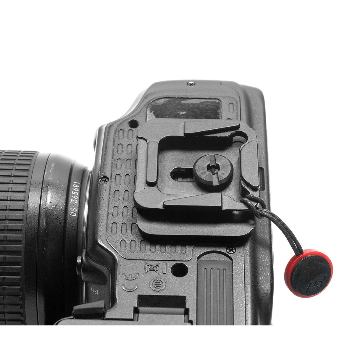 Czarna aparat DSLR z zamontowaną płytką statywową i czerwonym mocowaniem paska na białym tle.