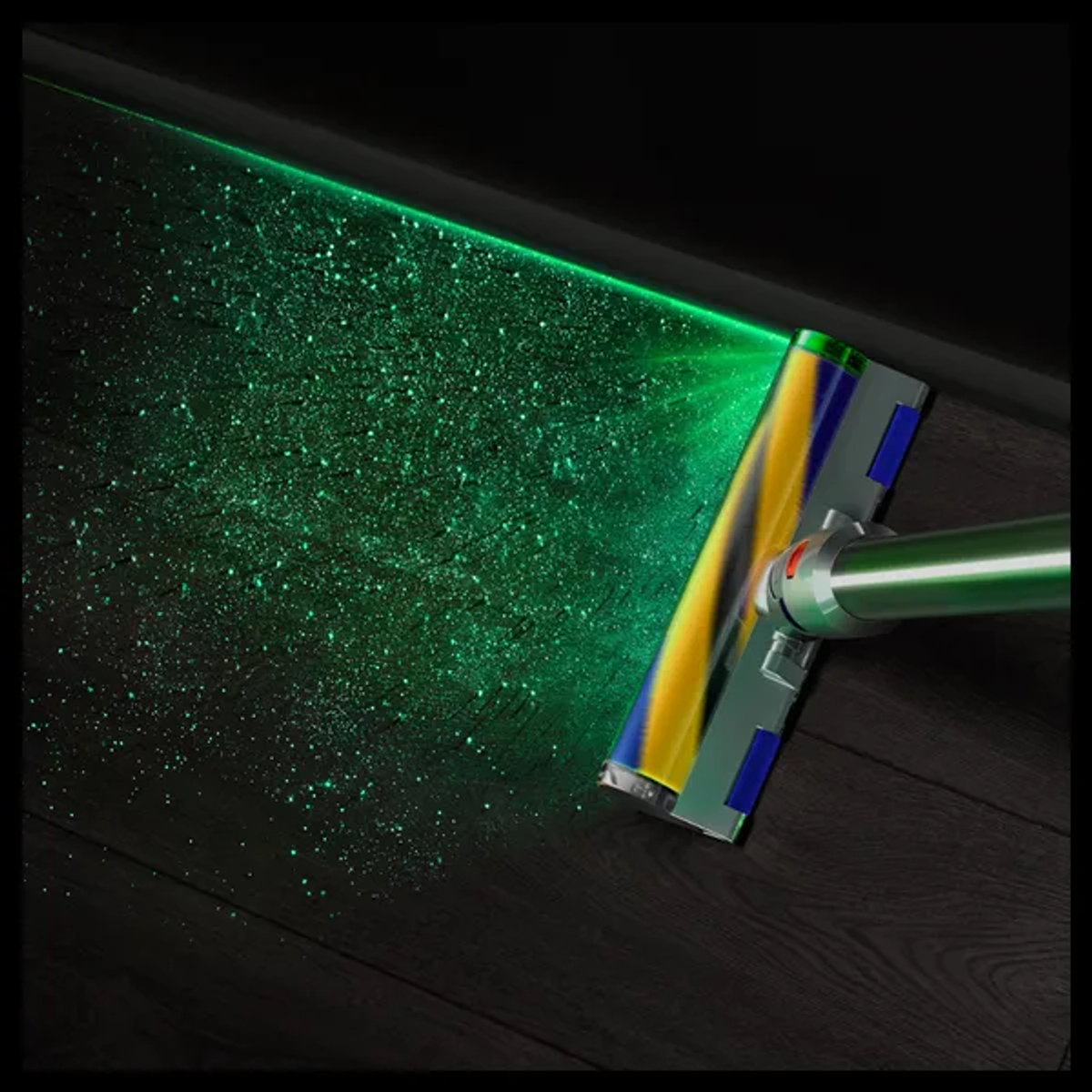 Una testina per aspirapolvere illumina la polvere fine su un pavimento in legno scuro con un raggio laser verde.