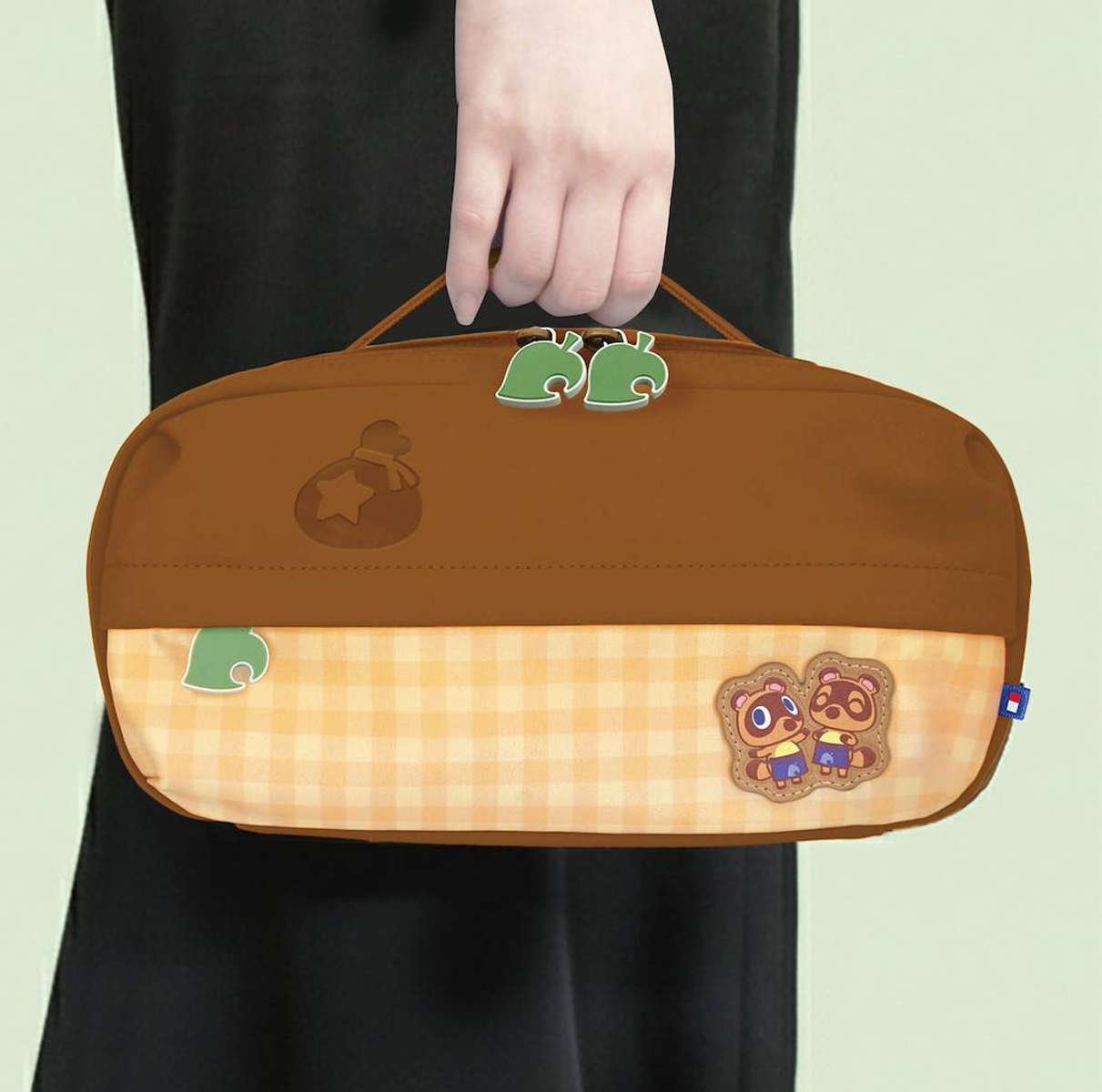 Un estuche marrón de Animal Crossing con cremalleras de hojas, icono de campana y parche de Timmy y Tommy.