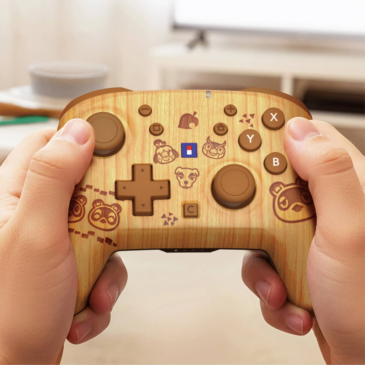 Kontroler do gier o wzorze drewna z postaciami z Animal Crossing trzymany w dłoniach.
