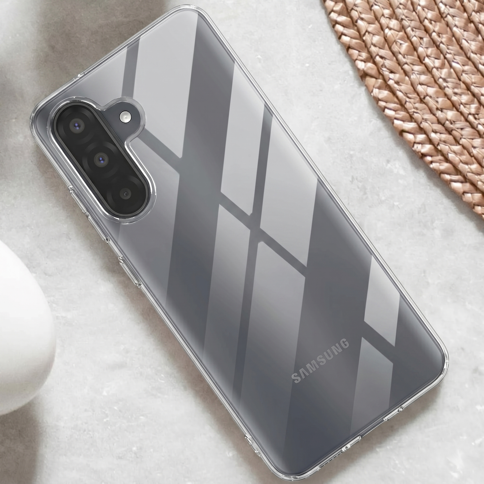 Rückseite eines Samsung-Smartphones mit Klarsichthülle, Dreifachkamera und Blitz auf hellem Hintergrund.