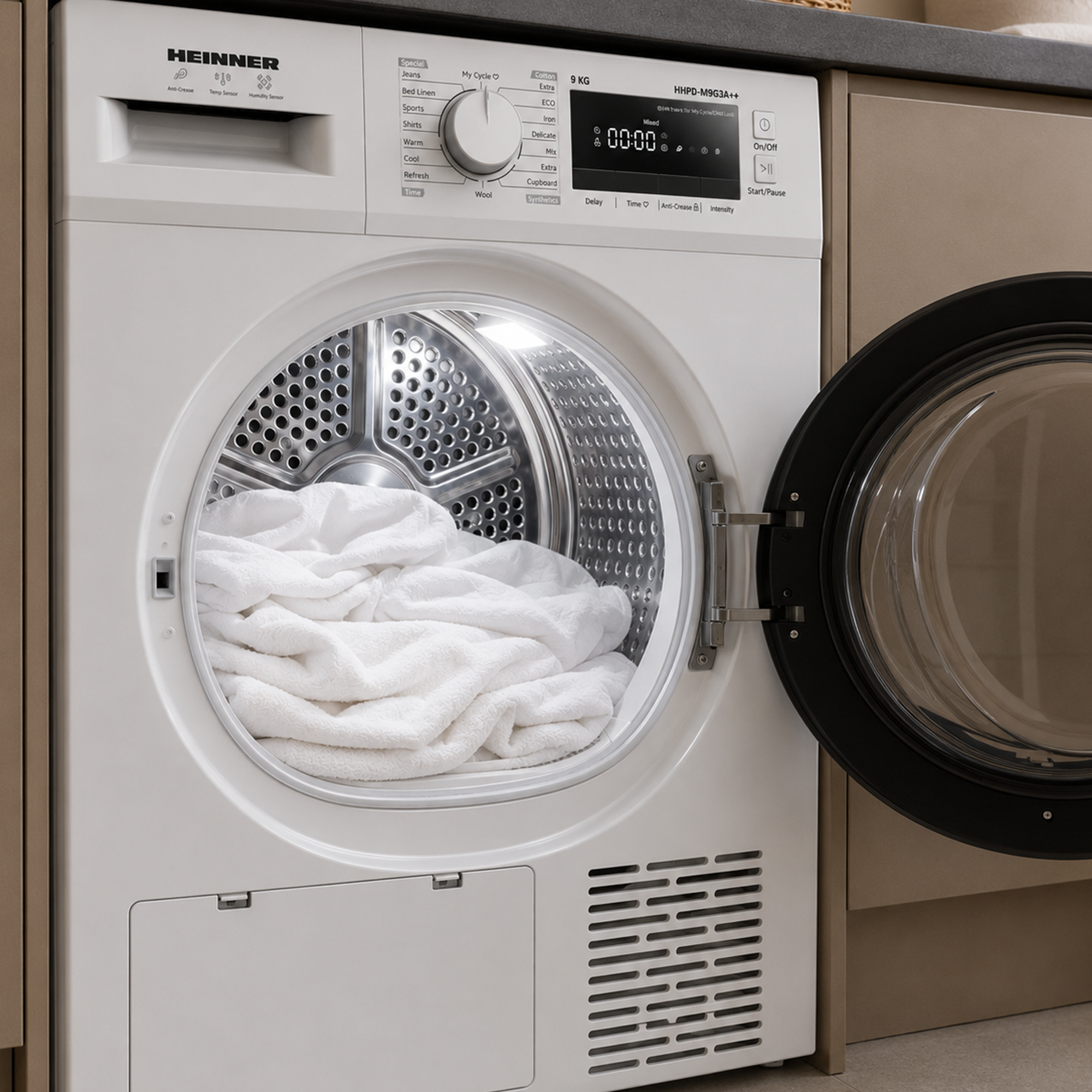 A white Heinner tumble dryer with an open door, an illuminated drum, and white laundry inside.