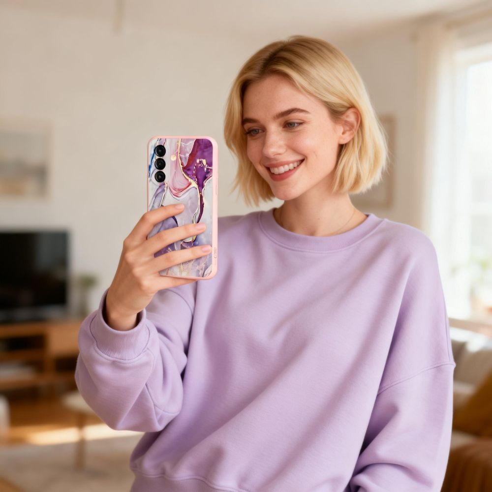Eine blonde Frau im lila Pullover macht ein Selfie mit einer marmorierten Handyhülle.