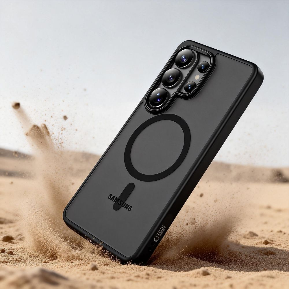 Ein schwarzes Samsung-Smartphone in Schutzhülle schlägt in der Wüste auf, Sand spritzt auf.