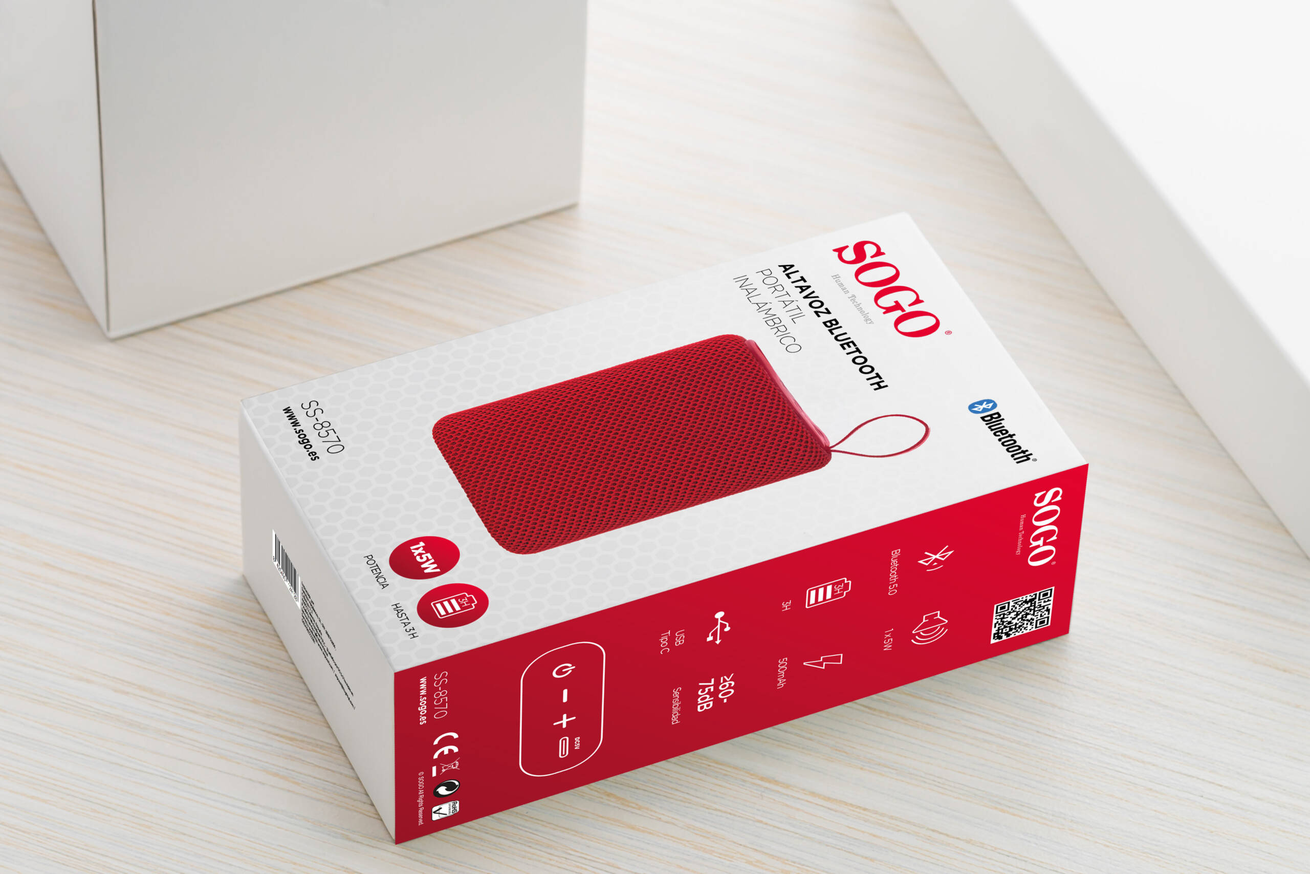 Una cassa per altoparlante Bluetooth Sogo rossa e bianca è posizionata su un tavolo in legno chiaro.