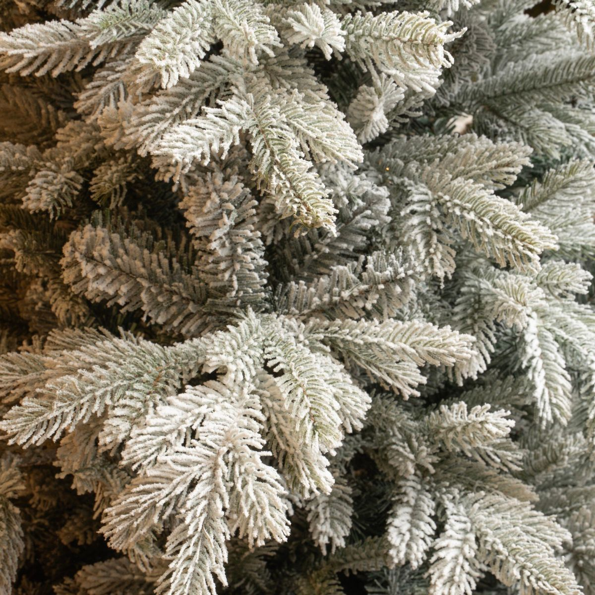 Close-up of dense, artificial snow-covered pine tree branches.
