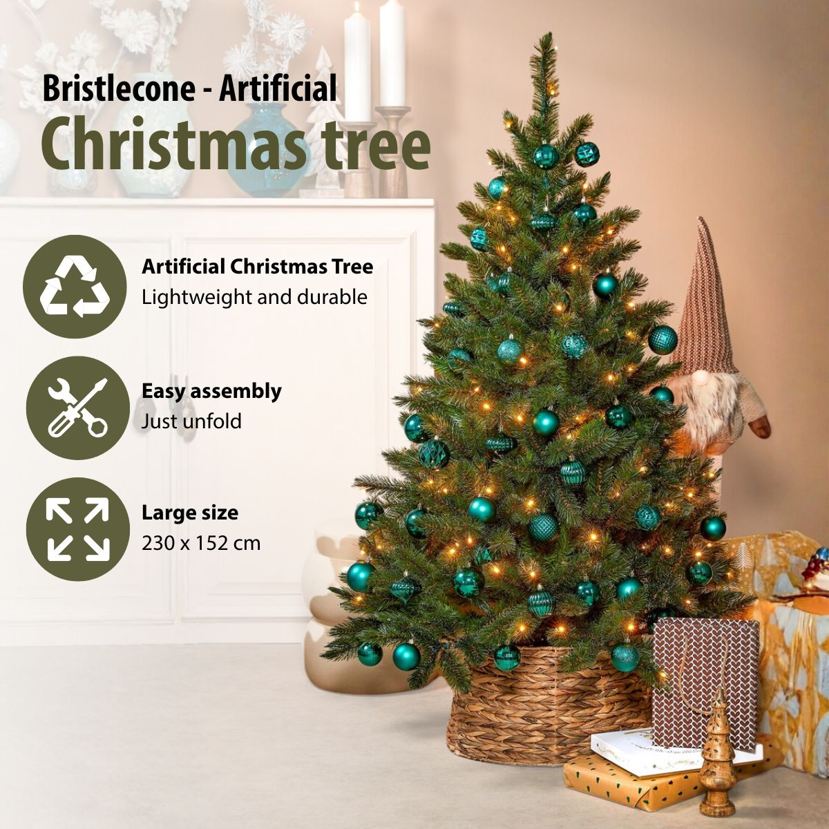 An artificial Christmas tree in a basket, decorated with blue baubles and lights, in front of a white cabinet.
