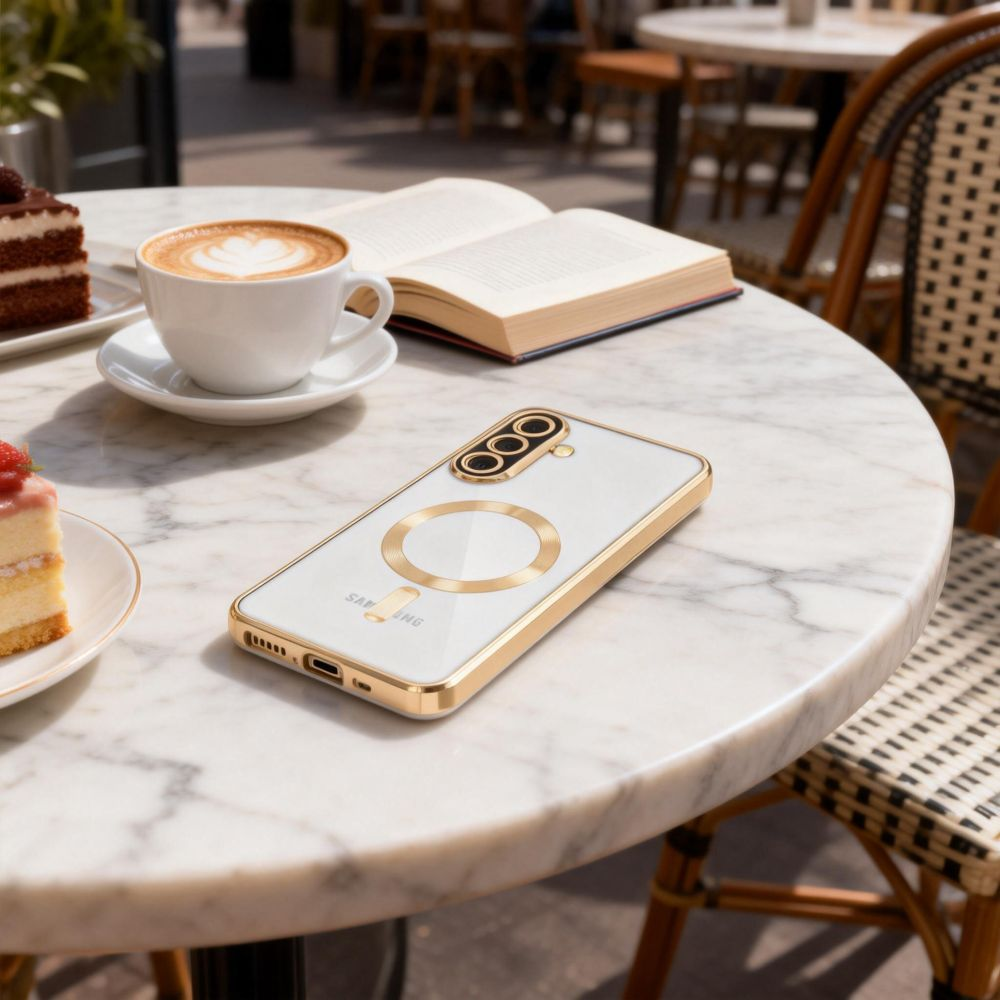 Ein Smartphone in Gold-Weiß liegt auf einem Marmor-Cafétisch neben Kaffee, Kuchen und einem offenen Buch.