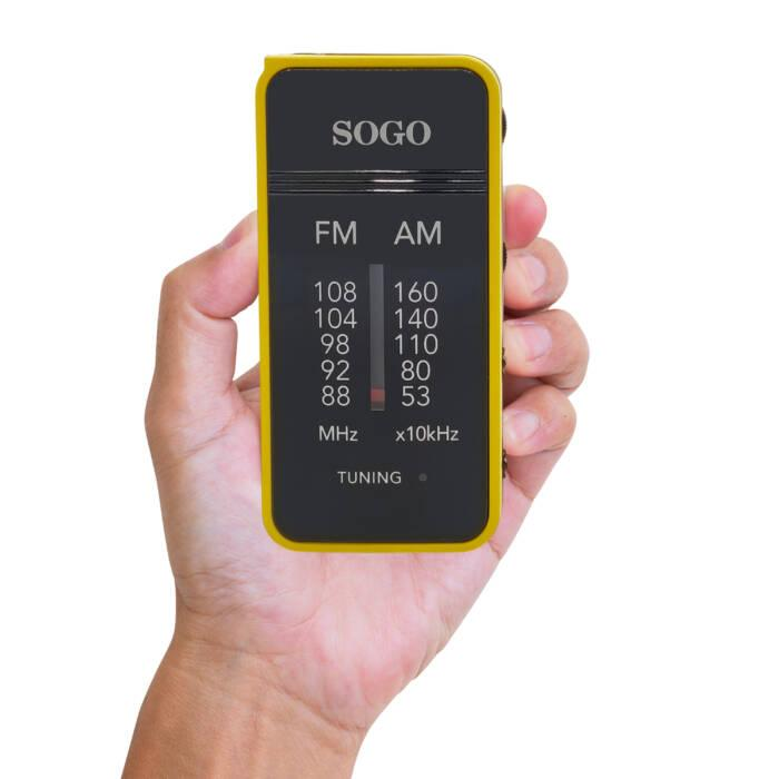 Una mano tiene una radio tascabile Sogo gialla e nera con scale FM e AM.