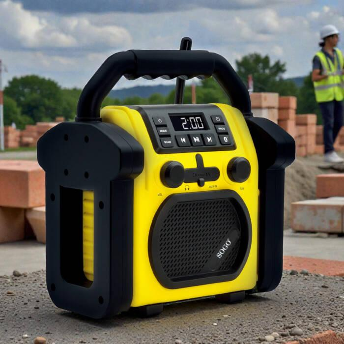 Una radio da cantiere gialla e nera su cemento, con un operaio sullo sfondo.