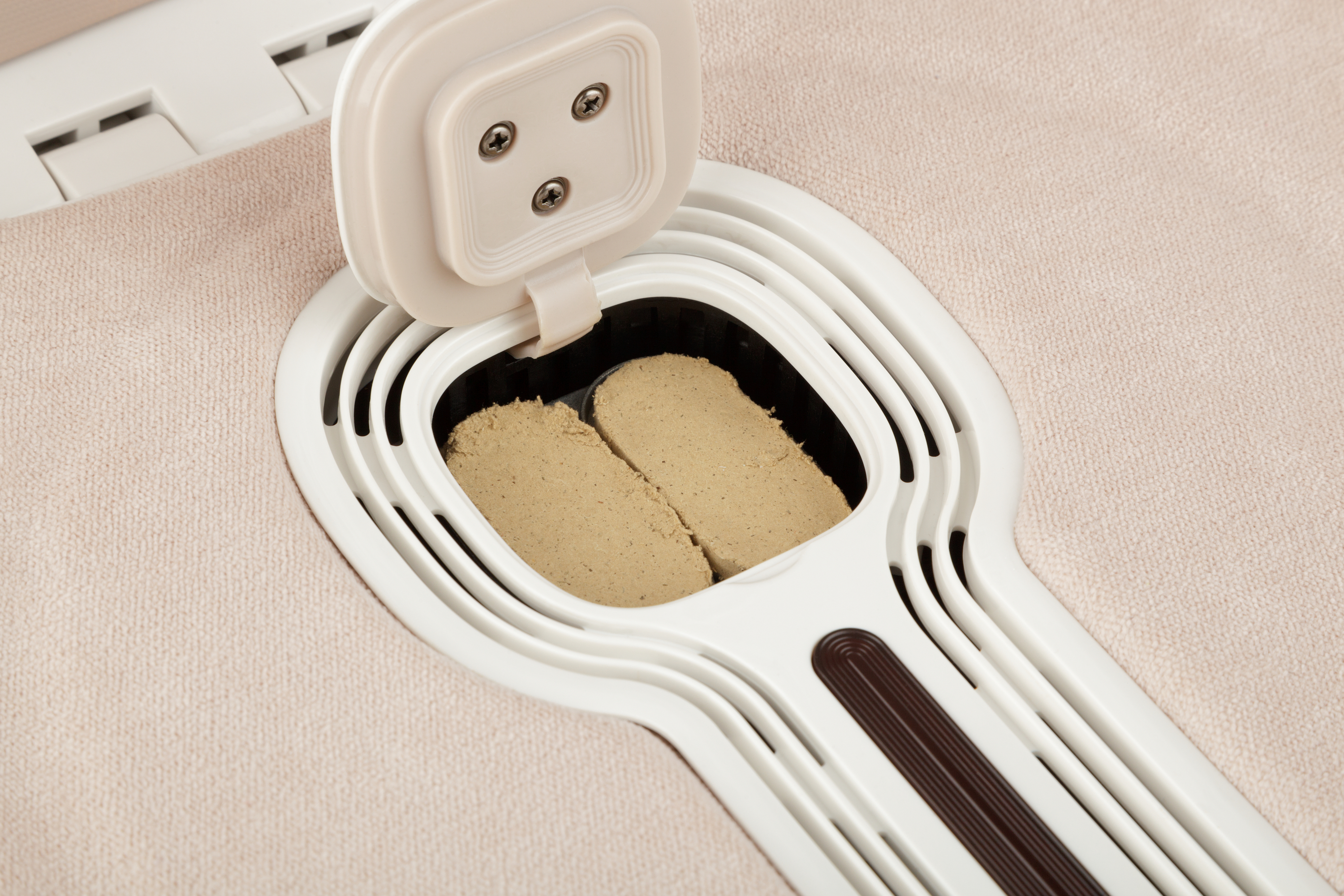 Un dispensador blanco abierto que contiene bloques beige sobre una superficie beige.