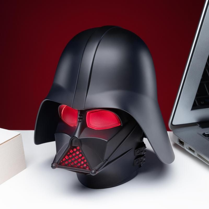 Un casco negro de Darth Vader con ojos y boquilla rojos brillantes sobre un escritorio blanco.