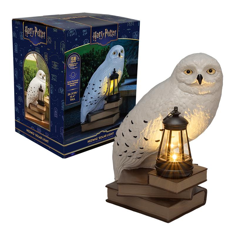 Luz solar Harry Potter Hedwig con una lechuza sobre libros y un farol, junto a su caja de embalaje azul.