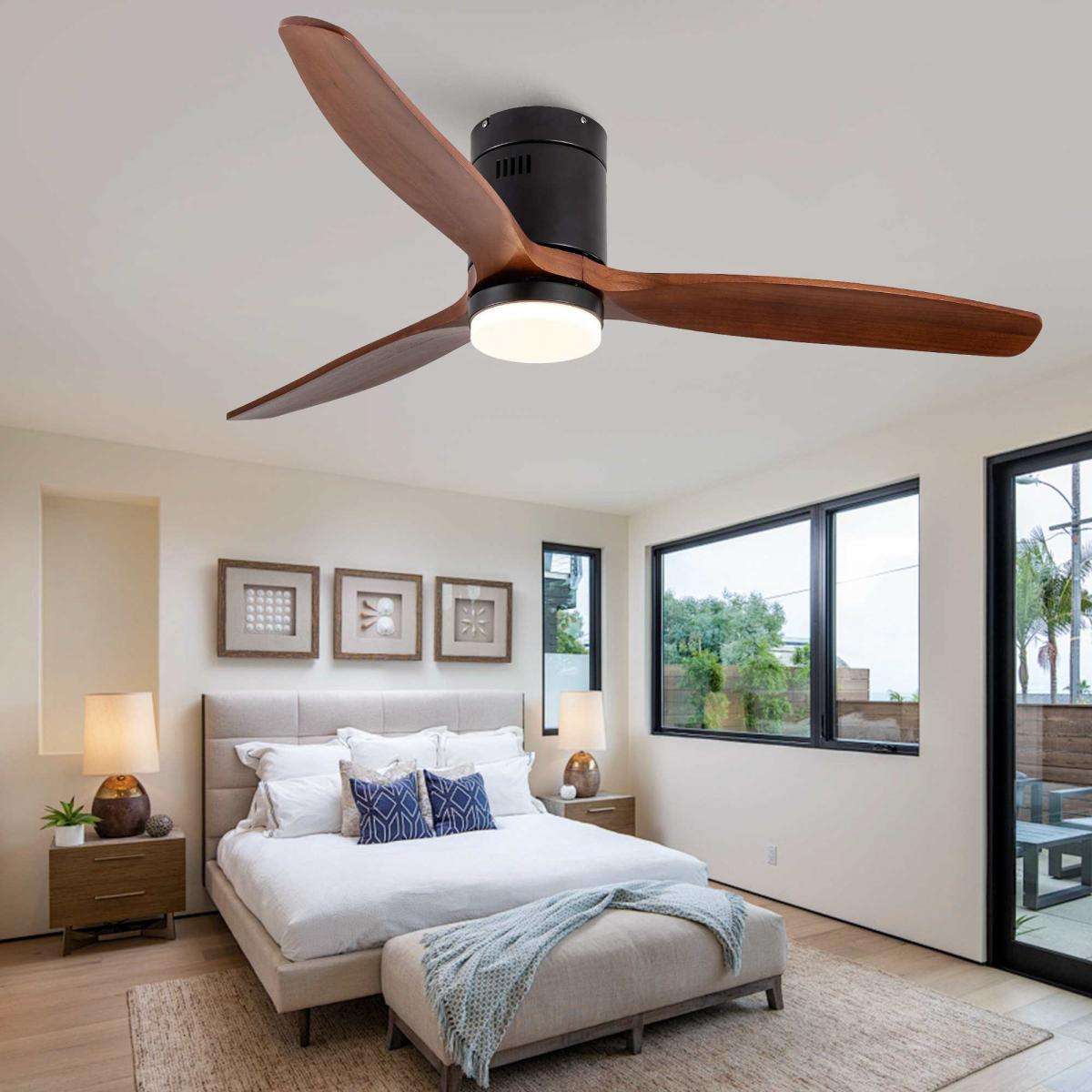 Moderne Deckenventilator mit drei braunen Holzflügeln und integrierter Beleuchtung in einem hellen Schlafzimmer.