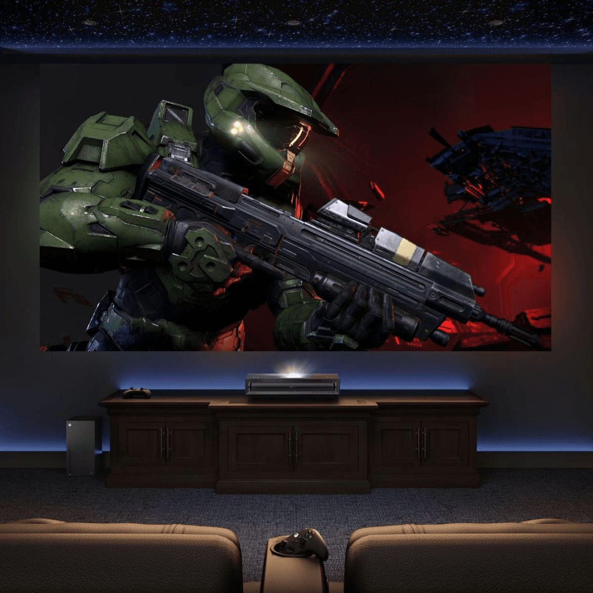 Cine en casa con Master Chief en pantalla, consola y sillones.
