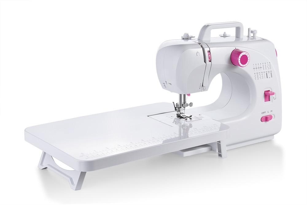 Eine weiße und rosa tragbare Nähmaschine mit angebautem Anschiebetisch auf weißem Hintergrund.