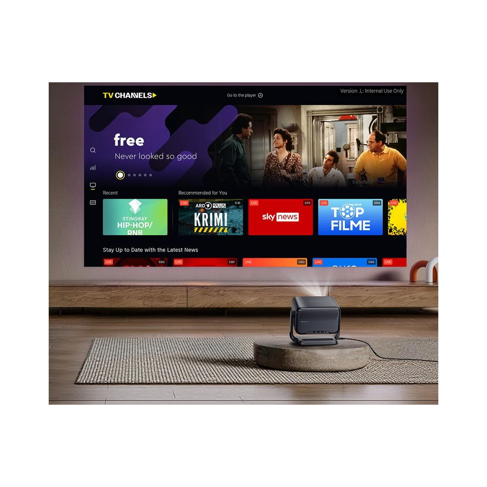 Ein Beamer projiziert ein TV-Menü auf eine weiße Wand über einem Holzregal.