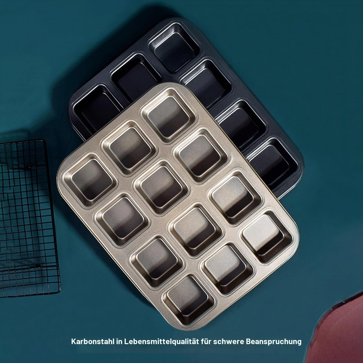 Zwei metallene Backformen mit quadratischen Mulden auf dunkler türkiser Oberfläche.