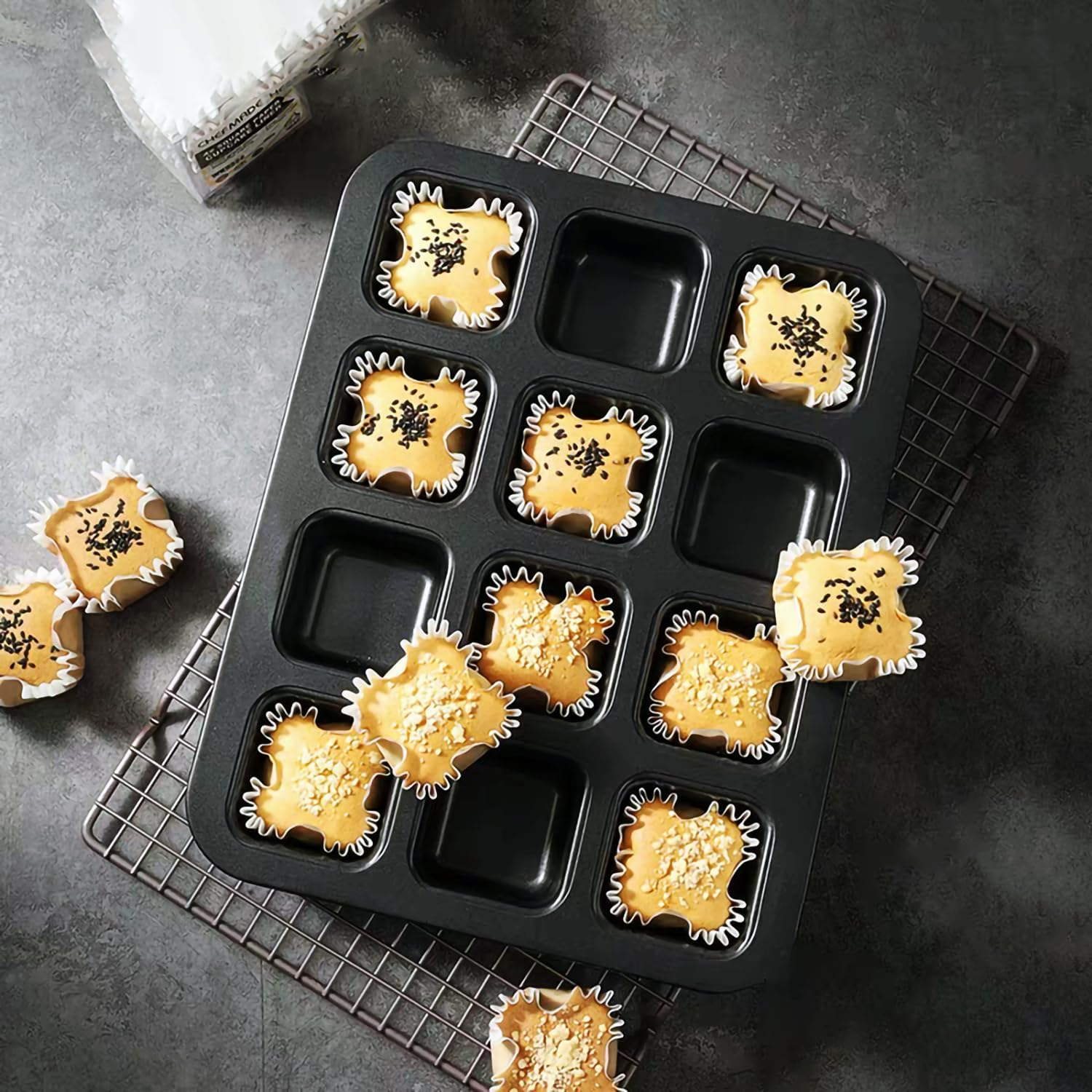Quadratische Muffins mit Toppings in einer Backform und auf einem Gitter auf grauem Untergrund.